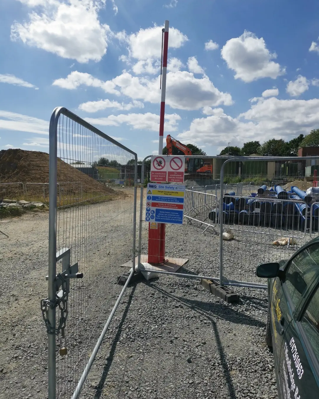 Construction site entrance barrier and safety signage with CCTV monitoring