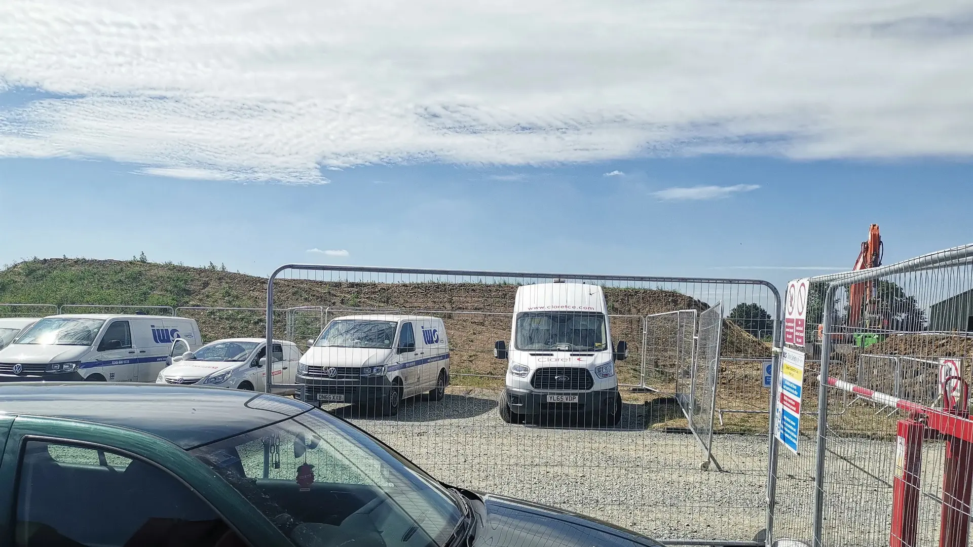 Construction site entrance with contractor vans and security fencing monitored by Safety Eye