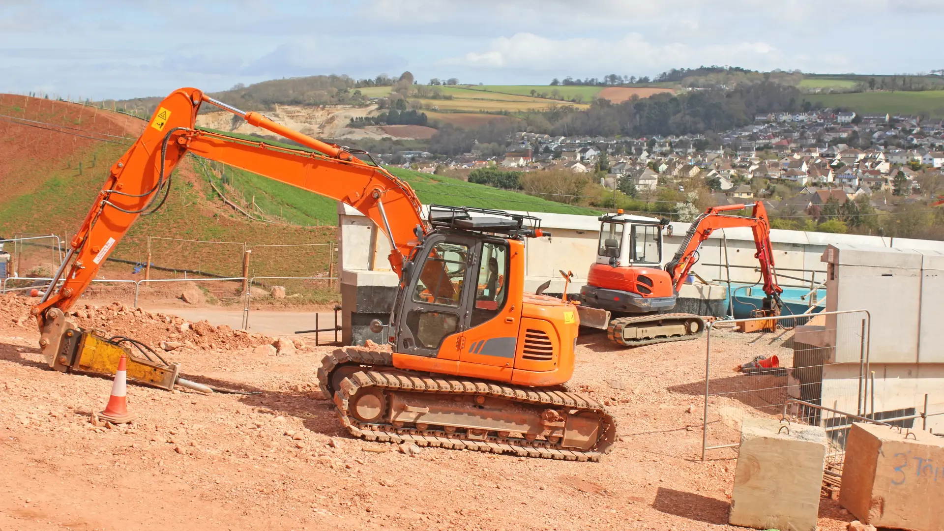 Orange excavators working on a construction site with onsite safety monitoring