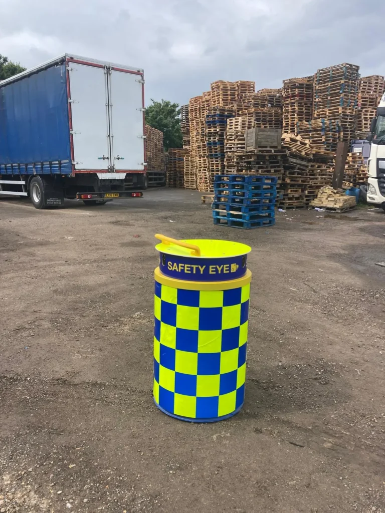 Safety Eye CCTV bollard at logistics yard with stacked pallets and delivery trucks